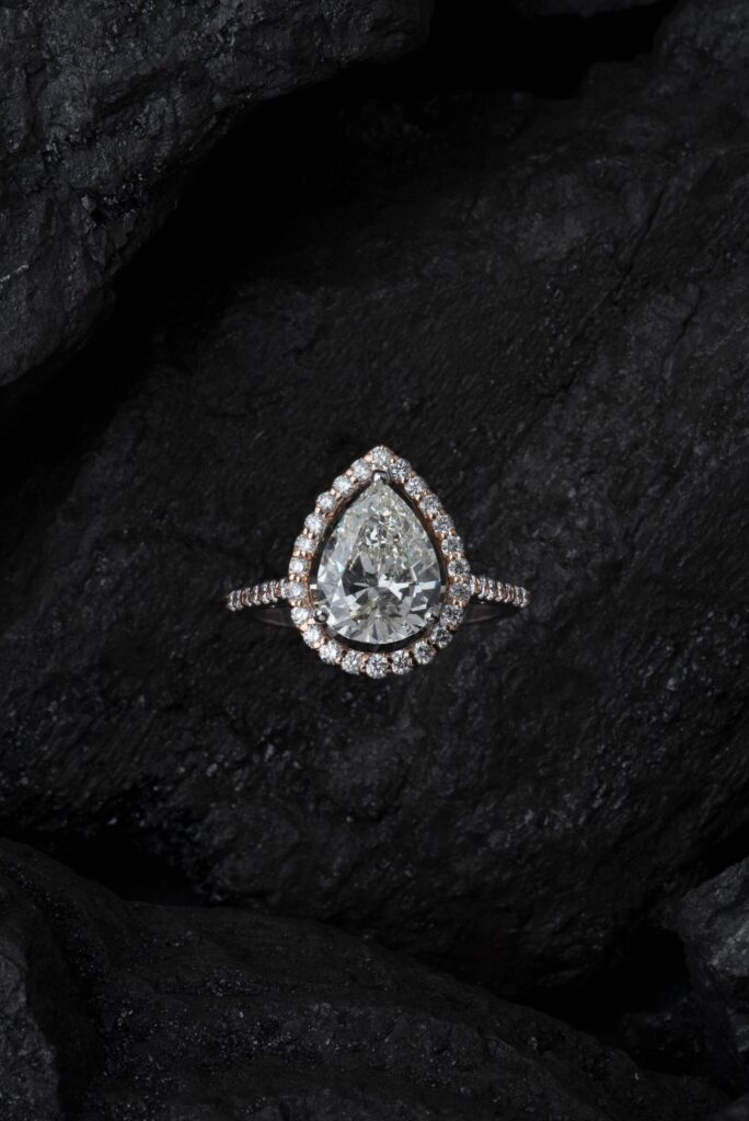 Teardrop-shaped diamond ring on a dark textured surface
